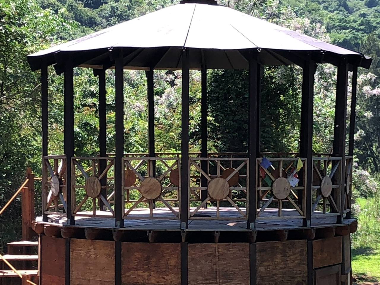 The open top storey of a double-storey rondavel: dark posts, a railing of wooden suns, and the roof above